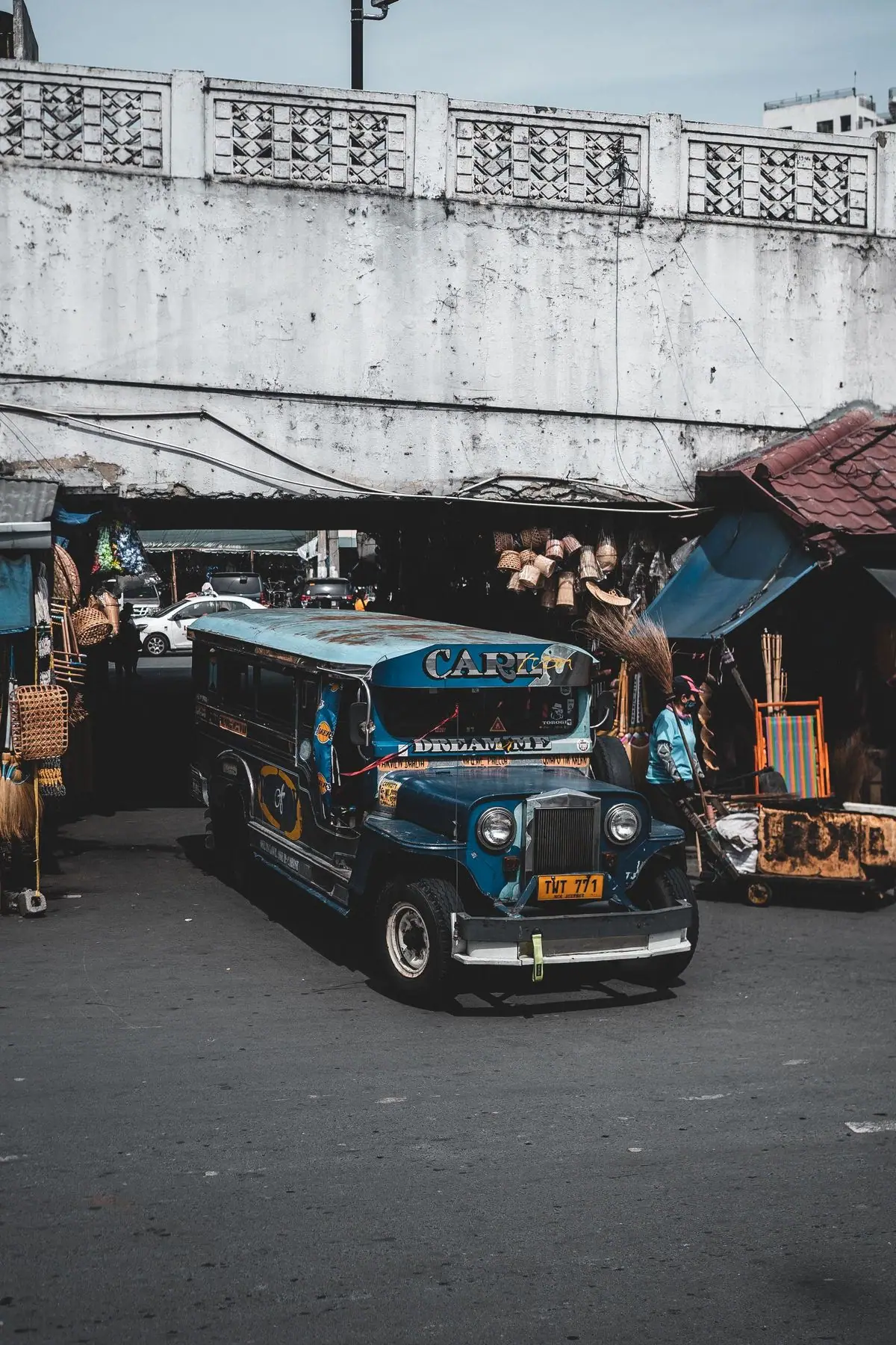Asul na jeepney sa ilalim ng concrete overpass sa Maynila.