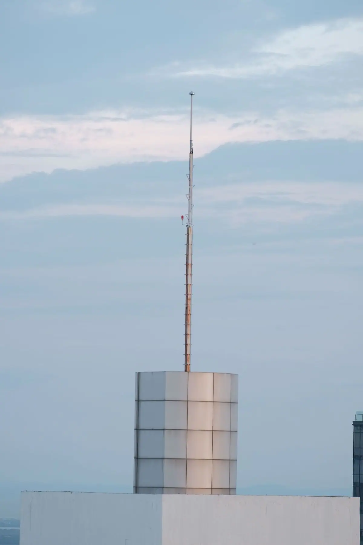 Mataas na antenna sa bubong ng gusali, sa ilalim ng maulap na langit sa Central Visayas.